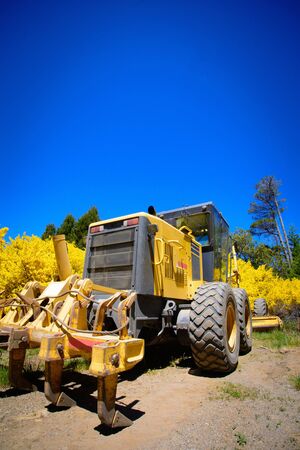 Yellow tractor with rake on the front on the farmland.の写真素材