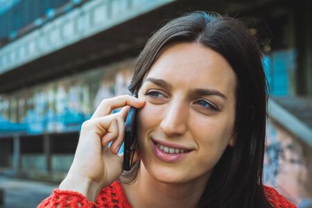 Portrait of young latin woman talking on her mobile phone. Outdoors.