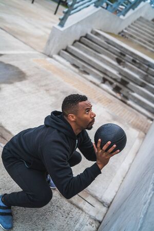 Portrait of an athletic man doing wall ball exercise outdoors. Sport and healthy concept.