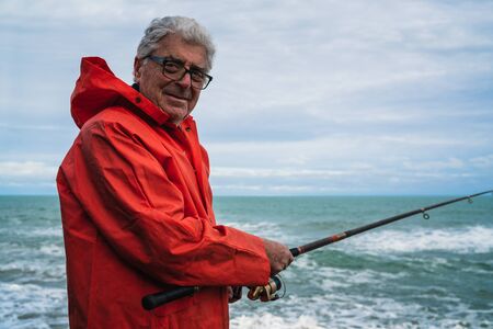 Portrait of an senior man fishing in the sea, enjoying life.  Fishing and sport concept.の写真素材