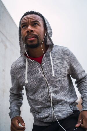 Portrait of a fitness man running with earphones outdoors. Sport, fitness and healthy lifestyle.の写真素材