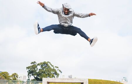 Portrait of a sport man jumping and doing exercise outdoors. Sport, fitness and healthy lifestyle.の写真素材