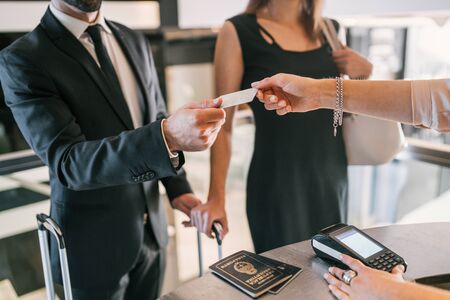 Close up of business people makes card payment at check-in at reception front desk. Business travel concept.の写真素材