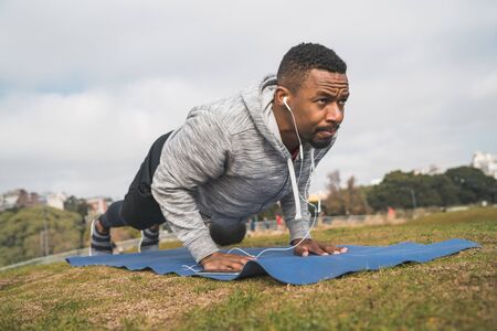 Portrait of an athletic man doing push ups at the park outdoors. Sport and healthy lifestyle concept.の写真素材
