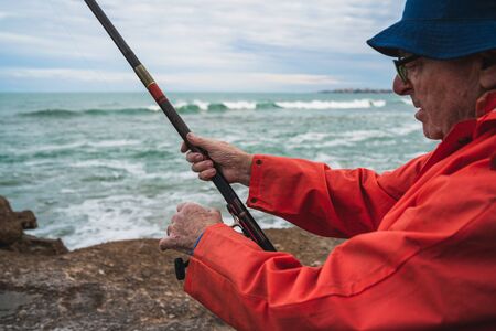 Portrait of an senior man fishing in the sea, enjoying life.  Fishing and sport concept.の写真素材