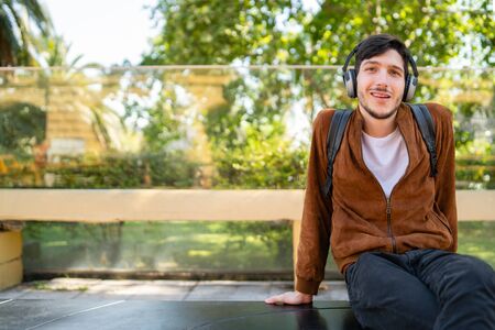 Portrait of young handsome man listening to music with earphones outdoors. Urban concept.の写真素材