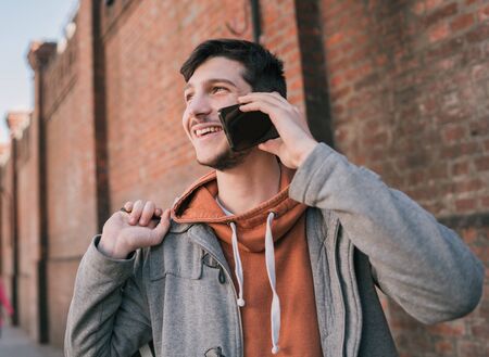 Portrait of young handsome man talking on the phone outdoors in the street. Urban concept....