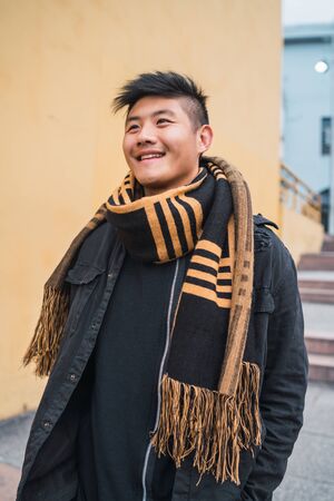 Portrait of young asian man looking confident and wearing winter clothes outdoors in the street. Urban concept.の写真素材