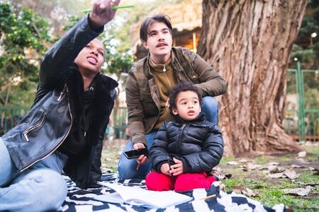 Portrait of cute mixed race ethnic family having a good time together at the park outdoors.