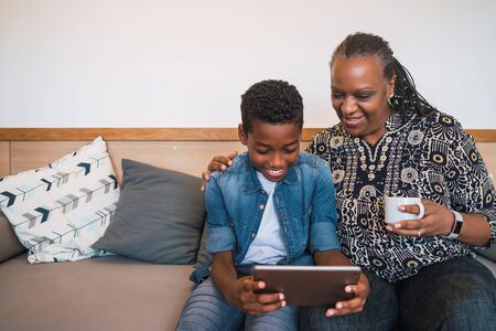 Portrait of grandmother and grandchild taking selfie with digital tablet while sitting on sofa couch...