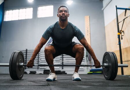 Portrait of young crossfit athlete doing exercise with a barbell. Crossfit, sport and healthy...