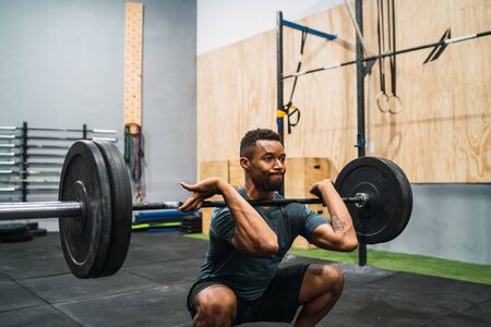Portrait of young crossfit athlete doing exercise with a barbell. Crossfit, sport and healthy lifestyle concept.の写真素材