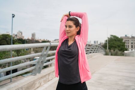 Portrait of an athletic woman stretching her arms before exercise outdoors. Sport and healthy...