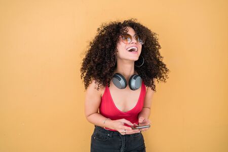 Portrait of young afro american latin woman wearing summer clothes and using her mobile phone....
