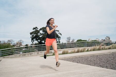 Portrait of a fitness woman running outdoors in the street. Sport and healthy lifestyle concept.