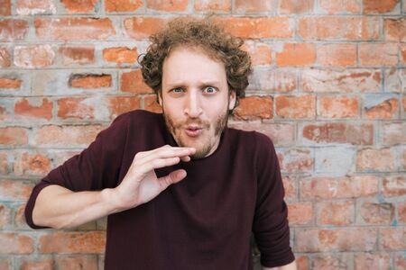 Portrait of young caucasian man against the brick wall in the street. Urban concept.の写真素材