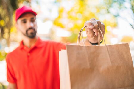 Portrait of a delivery man carrying packages while making home delivery to his customer. Delivery...