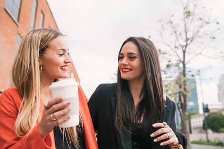 Portrait of two young friends spending good time together while walking outdoors at the street. Lifestyle and friendship concepts.の写真素材