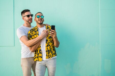 Portrait of happy gay couple spending time together and taking a selfie with mobile phone. Lgbt and...