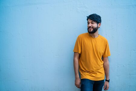 Portrait of attractive young beared man wearing summer clothes, standing against blue background.の写真素材