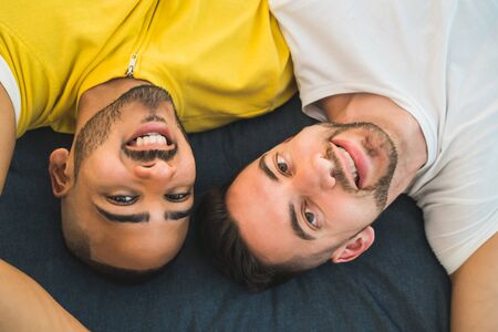 Portrait of a happy gay couple spending time and laying down on the floor. Lgbt and love concept.の写真素材