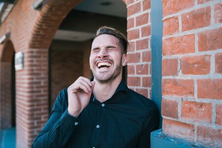 Portrait of young handsome man laughing and walking on the street. Urban concept.の写真素材