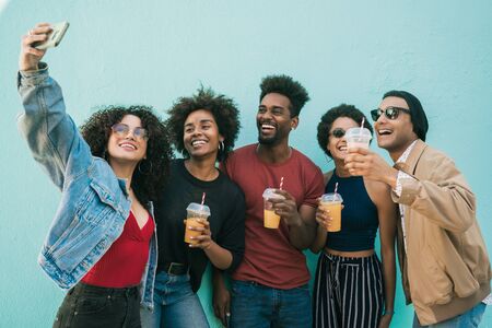 Portrait of multi-ethnic group of friends having fun together and taking a selfie while drinking fresh fruit juice.の写真素材