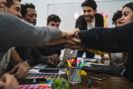 Team of work of creative designers showing unity with their hand together during meeting. Business and team work concept.の写真素材