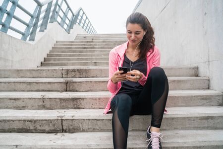 Portrait of an athletic woman using her mobile phone on a break from training. Sport and health...