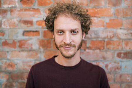 Portrait of young caucasian man against the brick wall in the street. Urban concept.の写真素材