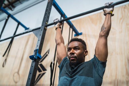 Portrait of an athletic man doing pull up exercise at the gym. Sport and healthy lifestyle concept.の写真素材