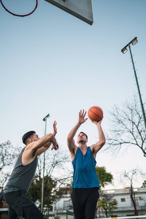 Young basketball players playing one-on-one on outdoor court. Sport and basketball concept.