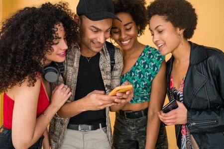Portrait of Afro friends having fun in the city and spending good time together while using their...