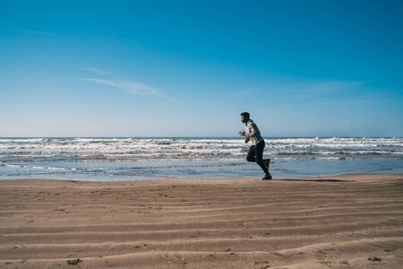 Portrait of an athletic man running at the beach. Sport, fitness and healthy lifestyle.
