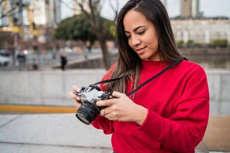Portrait of young photographer woman using a professional digital camera outdoors. Photography...