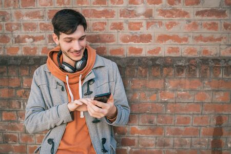 Portrait of young latin man using his mobile phone outdoors in the street. Communication concept.