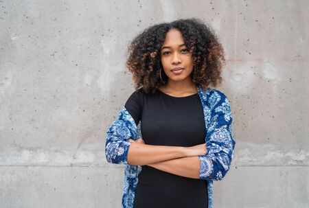 Portrait of beautiful young afro-american woman with curly hair against grey wall.の写真素材