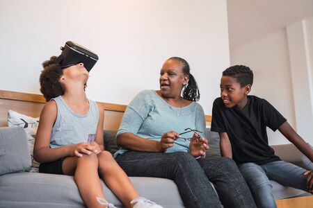 Portrait of African American grandmother and grandchildren playing together with VR glasses at home. Family and technology concept.の写真素材