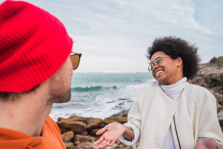 Portrait of two young friends spending good time together and having fun with the sea in the...