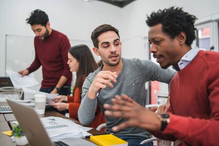 Two creative designers working in a project together and sharing new ideas on workplace. Business...