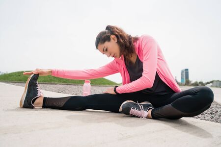 Portrait of an athletic woman stretching legs before exercise outdoors. Sport and healthy lifestyle.