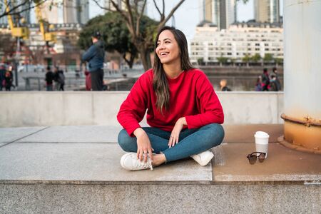 Portrait of young latin woman sitting outdoors with a cup of coffee. Urban concept.