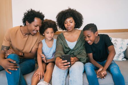 Portrait of African American family taking a selfie together with mobile phone at home. Family and...