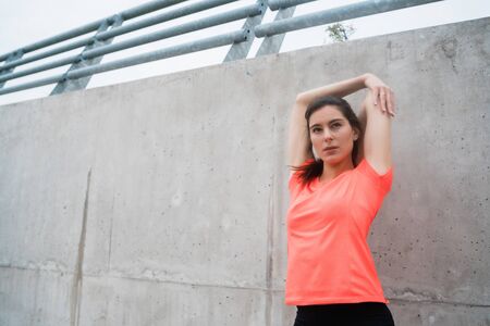 Portrait of an athletic woman stretching her arms before exercise outdoors. Sport and healthy...