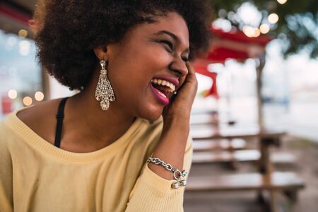 Close-up of a beautiful afro american latin woman smiling and spending nice time at the coffee shop.の写真素材