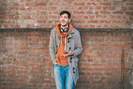 Portrait of young latin man using his mobile phone outdoors in the street. Communication concept.の写真素材