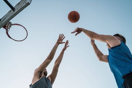 Young basketball players playing one-on-one on outdoor court. Sport and basketball concept.の写真素材