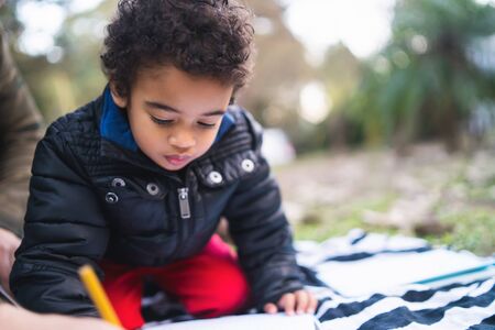 Portrait of cute african american little boy having fun and playing outdoors in the park.の写真素材