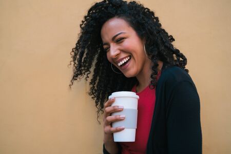 Portrait of young afro american woman looking confident and posing while holding a cup of coffee...