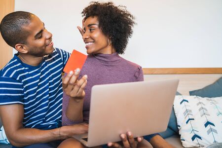 Portrait of happy young couple shopping online with credit card and laptop at home. Shop online and...
